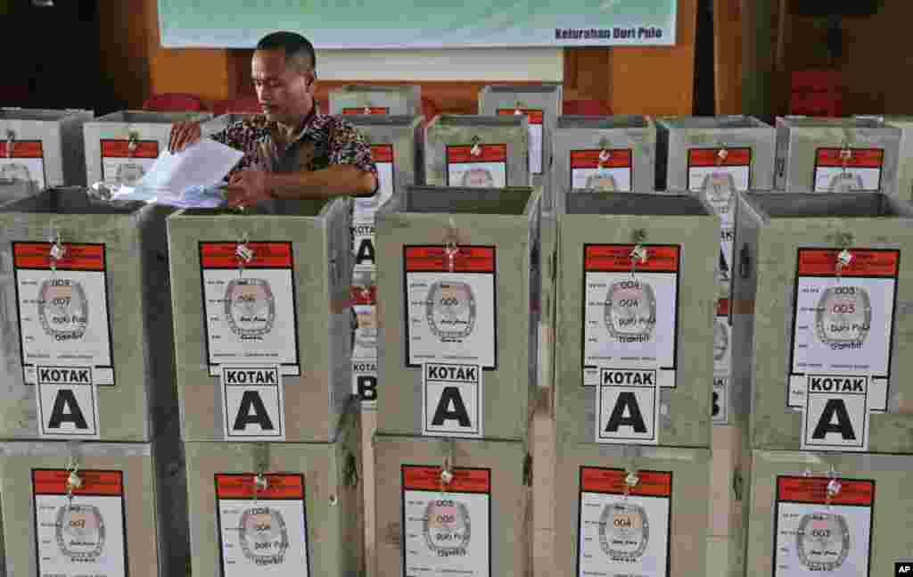 Seorang petugas pemilu memilih-milih kertas suara untuk dimasukkan ke dalam kotak-kotak yang akan dibagikan di TPS-TPS di Jakarta (7/7). (AP/Tatan Syuflana)