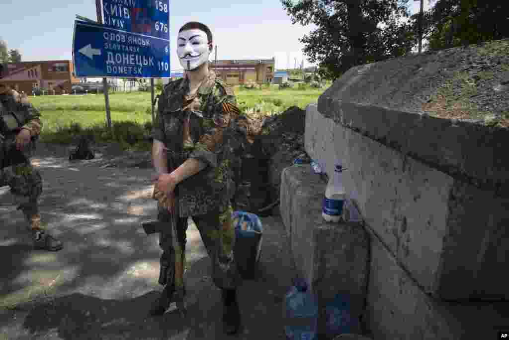 A masked pro-Russian militant stands behind the barricades at a checkpoint blocking the major highway outside Kharkiv, eastern Ukraine, May 17, 2014.