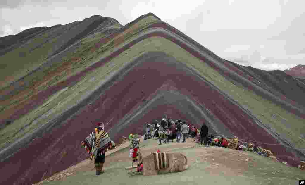 An Andean man rests with his llama while tourists take in the natural wonder of Rainbow Mountain in Pitumarca, Peru. Tourists gasp for breath as they climb for two hours to the 16,404-foot (5,000-meter) peak in the Peruvian Andes, but stunned by the magical beauty that unfurls before them.