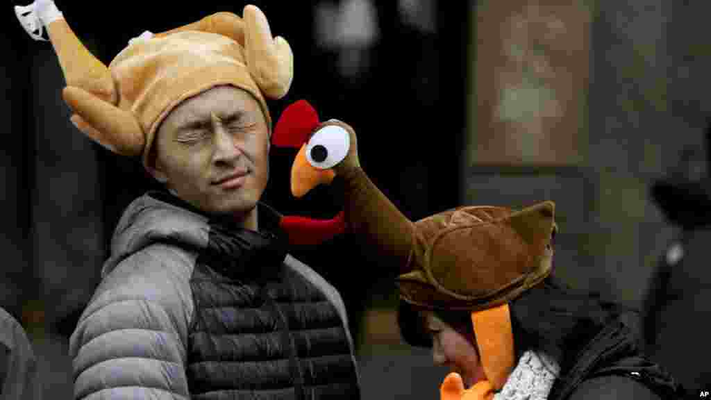 Tamari Hedani, kanan, memukul pacarnya, Chris Chu, keduanya dari San Francisco, dengan topi turki sebelum acara Parade Hari Thanksgiving Macy dimulai di New York, 27 November 2014.