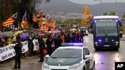 FILE - Demonstrators wave esteladas or independence flags as a bus of the Spain's Civil Guard carrying the nine Catalonian politicians and activists, leaves the Brians II prison, in Barcelona, Spain, Feb.1, 2019.