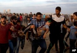 Palestinians carry 12 year-old boy, Fares Sersawi, who died later from his wound after being shot by Israeli troops during a protest at the Gaza Strip's border with Israel, Oct. 5, 2018.