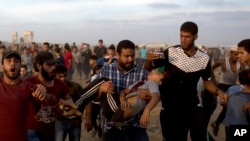 Palestinians carry 12 year-old boy, Fares Sersawi, who died later from his wound after being shot by Israeli troops during a protest at the Gaza Strip's border with Israel, Oct. 5, 2018. 