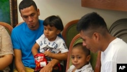 In this image taken from video, Javier Garrido Martinez, left and Alan Garcia, right, sit with their 4-year-sons at a news conference in New York, Wednesday, July 11, 2018. They men were reunited with their children after almost two months of separation, Authorities took their boys them when they stopped at the U.S. southern border. (AP Photo/Robert Bumsted)