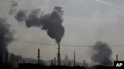 FILE - In this Dec. 10, 2018 photo, smokestacks near an oil refinery are seen. 