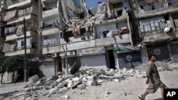 Cư dân đi ngang qua một tòa nhà bị phá hủy trong các vụ không kích ở Aleppo, Syria.