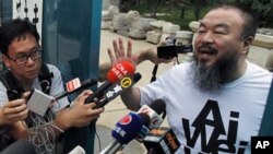 Activist artist Ai Weiwei gestures while speaking to journalists gathered outside his home in Beijing, June 23, 2011