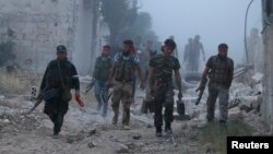 Rebel fighters from the Islamic Front walk amidst smoke during what they said was an offensive against forces loyal to Syria's President Bashar al-Assad in Maarat Al-Nouman, Idlib province, May 5, 2014. 