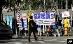 Pedestrians pass by as demonstrators with the Falun Gong protest group stand near the hotel where Chinese President Xi Jinping is staying Tuesday, Sept. 22, 2015.