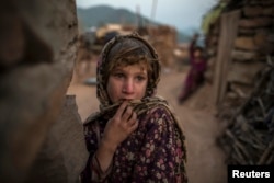 FILE - Soniya, 6, whose family moved to Islamabad from Pakistan's Khyber-Pakhtunkhwa province to look for work, stands outside their house on the outskirts of Islamabad.