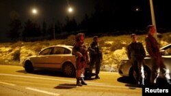 Israeli soldiers stand guard near the Jewish settlement of Otniel in the West Bank, Jan. 17, 2016, after a female resident of the settlement was stabbed to death in her home.