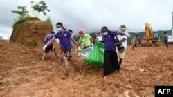 Myanmar soldiers and Red Cross workers carry out a body recovered from the site of a landslide by jade mines near Hpakant in Kachin state on July 4, 2020. - Dozens of jade miners have been buried in a mass grave after a landslide in northern Myanmar kille