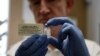 FILE - A researcher holds a vial of an experimental Ebola vaccine in Oxford, England, Sept. 17, 2014.