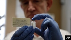 FILE - A researcher holds a vial of an experimental Ebola vaccine in Oxford, England, Sept. 17, 2014.