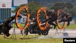 FILE - People's Liberation Army (PLA) soldiers jump through rings of fire during a war game performance for the public on an open day at the Shek Kong Barracks in Hong Kong, June 30, 2013. 