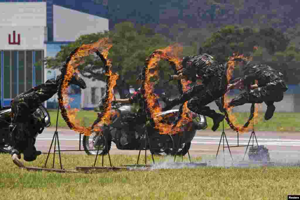 People&#39;s Liberation Army soldiers jump through rings of fire during a war game performance for the public on an open day at the Shek Kong Barracks in Hong Kong. 