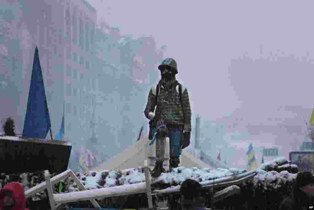 A young man stands on barricades defended by Pro-European Union activists next to government buildings in Kyiv, Dec. 9, 2013.