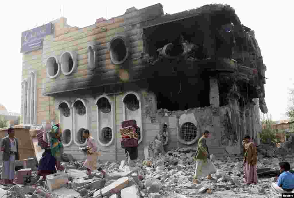 People salvage belongings from a government bank that was hit during an airstrike in Yemen&#39;s northwestern city of Saada, April 16, 2015.