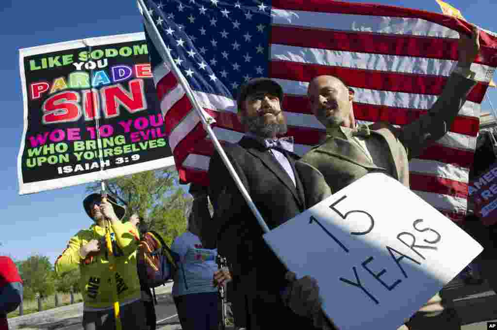 Joe Capley-Alfano, center, and his husband Frank Capley-Alfano, who've been together 15 years and married seven, hold an American flag in front of the Supreme Court in Washington, April 28, 2015.