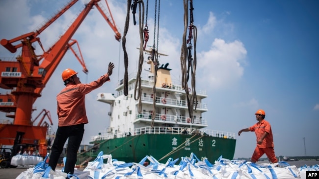 在中国江苏省张家港的一个港口，工人们正在卸载装着化学品的袋子。