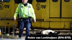 NETHERLANDS -- An armed policeman and a body (R) are seen at the scene where a shooting took place at the 24 Oktoberplace in Utrecht, March 18, 2019