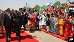 Chinese President Xi Jinping waves to children with Pakistan's Present Mamnoon Hussain, left, at Nur Khan airbase in Islamabad, Pakistan, April 20, 2015.
