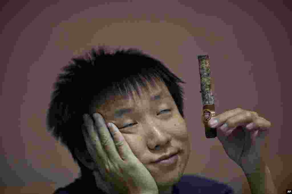 A participant in the competition for the longest ash holds his cigar during the XVI Cuba Cigar festival, in Havana.