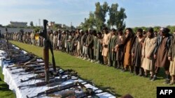Para kombatan ISIS dan senjata yang disita setelah mereka menyerahkan diri kepada pemerintah Afghanistan, di Jalalabad, Provinsi Nangarhar, 17 November 2019. (Foto: AFP)