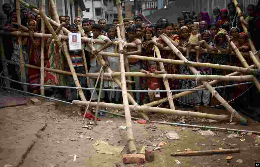 Curious onlookers and relatives of missing victims watch from behind a make shift fence as workers start dislodging parts of the garment factory building which collapsed in Savar, near Dhaka, April 29, 2013. 