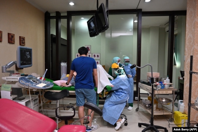 Dokter kandungan (tengah) dan perawat memakai alat pelindung saat memeriksa ibu hamil ,Jakarta, 22 April 2020, sebagai ilustrasi. (Foto: AFP/Adek Berry)