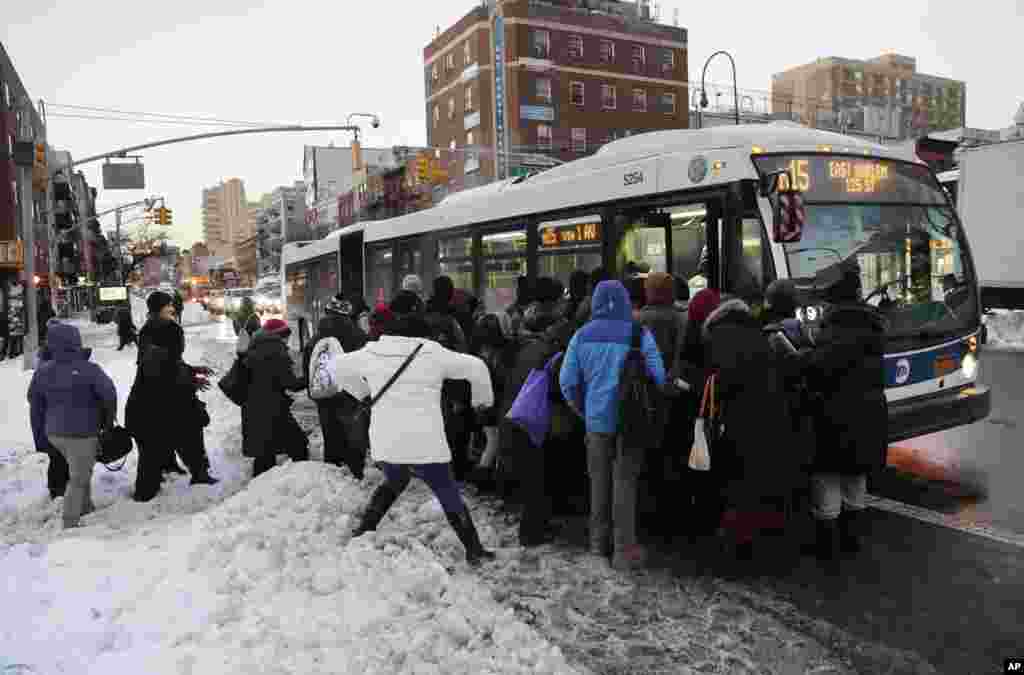 Warga pengguna transportasi umum melalui tumpukan salju ketika naik bis di New York, 25 Januari 2016. Badai salju sepanjang akhir pekan mendera Gulf Coast hingga ke New England, menyulitkan perjalanan.