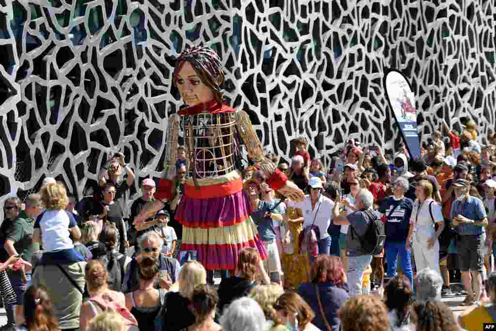 &quot;Little Amal,&quot; a huge puppet representing a Syrian refugee girl traveling 8,000 kilometers across Turkey and Europe, is carried along the Mucem museum in Marseille, Sept. 22, 2021, as part of &quot;The Walk,&quot; a festival of art.