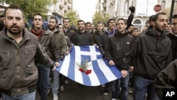 Students carry a blood-stained Greek flag during a rally in Athens marking the anniversary of a 1973 students uprising against the dictatorship then ruling Greece November 17, 2011