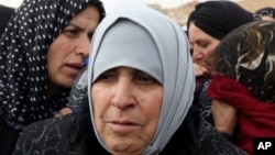 FILE - Umm Mohammed, 68, cries during an interview with The Associated Press as hundreds of Syrian women stand in line waiting to collect aid from relief agencies helping Syrian refugees.