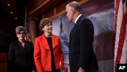 Sen. Jeanne Shaheen, D-N.H., center, and Sen. Joni Ernst, R-Iowa, left, talk with Sen. Thom Tillis, R-N.C., right, on Capitol Hill in Washington, Feb. 7, 2018,