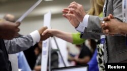 Corporate recruiters (R) gesture and shake hands as they talk with job seekers at a Hire Our Heroes job fair targeting unemployed military veterans and sponsored by the Cable Show, a cable television industry trade show in, Washington, June 11, 2013.