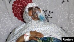 FILE - A woman breathes through an oxygen mask at al-Quds hospital, after a hospital and a civil defense group said a gas, what they believed to be chlorine, was dropped alongside barrel bombs on a neighborhood in Aleppo, Syria, Aug. 11, 2016.