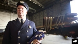 Bob McGovern, with the St. James, N.Y. Fire Department, holds the American Flag while waiting for a piece of steel to be loaded on a flatbed truck at John F. Kennedy International Airport, June 16, 2011 in New York.