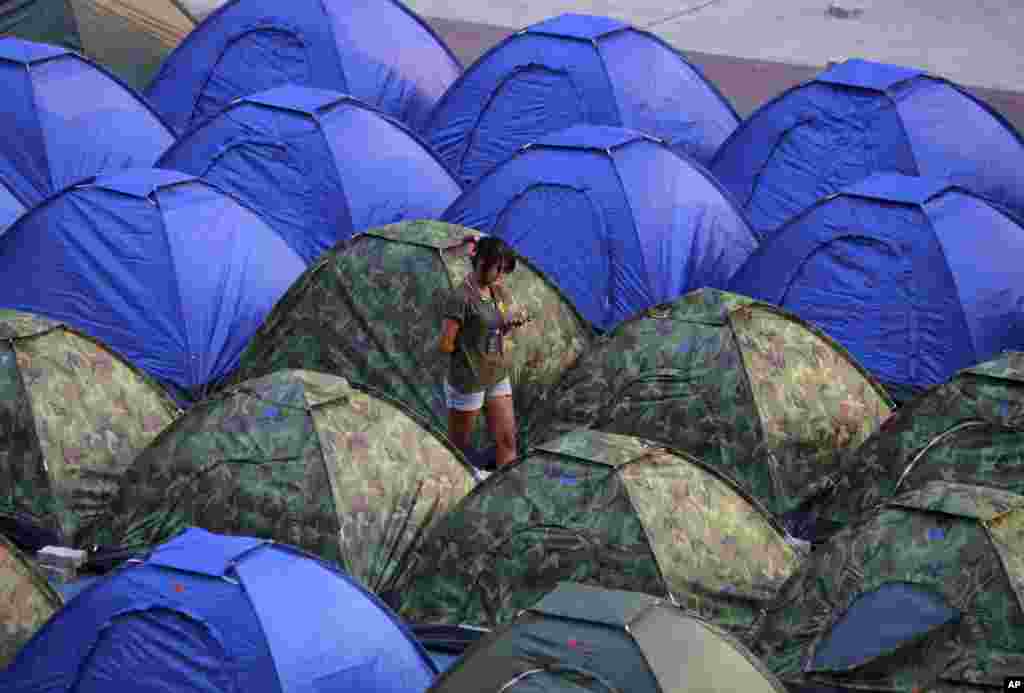 An anti-government protester checks message from her mobile phone in the middle of tents at a rally site in Bangkok, Thailand. 