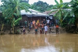 Rohingya refugees look at flood water following heavy rains at the Rohingya refugee camp in Kutupalong, Bangladesh, Wednesday, July 28, 2021.