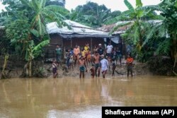 Rohingya refugees look at flood water following heavy rains at the Rohingya refugee camp in Kutupalong, Bangladesh, Wednesday, July 28, 2021.