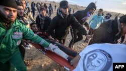 Les manifestantas palestiniens transportent un blessé près de la frontière avec l'Israel.
