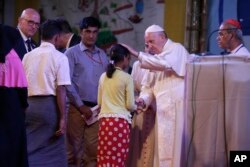 Pope Francis interacts with a Rohingya Muslim refugee at an interfaith peace meeting in Dhaka, Bangladesh, Dec. 1, 2017.