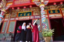 Mahasiswa Muslim Thailand berfoto selfie saat berkunjung ke kuil China menjelang Tahun Baru Imlek di provinsi Narathiwat, Thailand selatan, 11 Februari 2021. (Foto: TOHLALA / AFP)