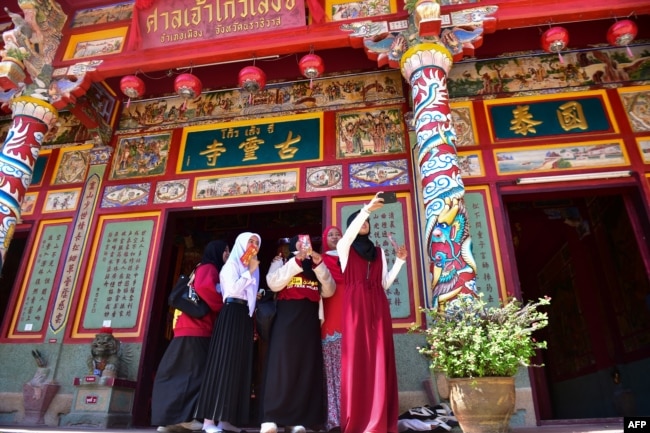 Mahasiswa Muslim Thailand berfoto selfie saat berkunjung ke kuil China menjelang Tahun Baru Imlek di provinsi Narathiwat, Thailand selatan, 11 Februari 2021. (Foto: TOHLALA / AFP)