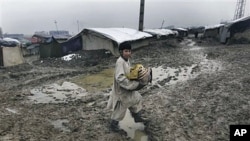 An Afghan boy from a poor neighborhood carries bread on his way home as it rains in Kabul, Afghanistan, February 23, 2011