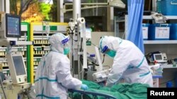 中國湖北省武漢大學中南醫院的醫生身穿防護服治療一名新冠病毒肺炎病患。（2020年1月28日）