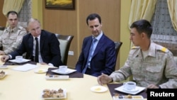 Russian President Vladimir Putin (2nd L) and Syrian President Bashar al-Assad (2nd R) meet with servicemen as they visit the Hmeymim air base in Latakia Province, Syria, Dec. 11, 2017. 