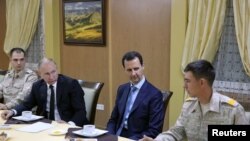 Russian President Vladimir Putin (2nd L) and Syrian President Bashar al-Assad (2nd R) meet with servicemen as they visit the Hmeymim air base in Latakia Province, Syria, Dec. 11, 2017. 