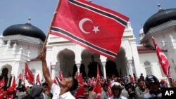 An Acehnese man waves a Crescent-Star flag during a rally outside Baiturrahman Grand Mosque in Banda Aceh, Aceh province, Indonesia, April 1, 2013.